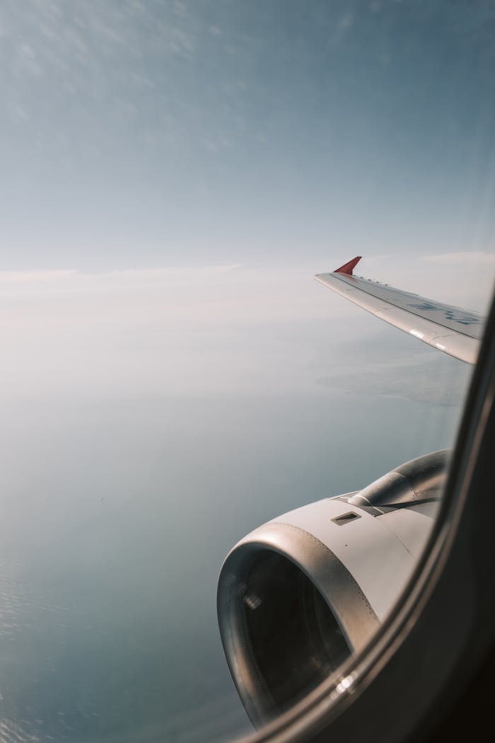 View Of White Airplane Wing Over The Clouds